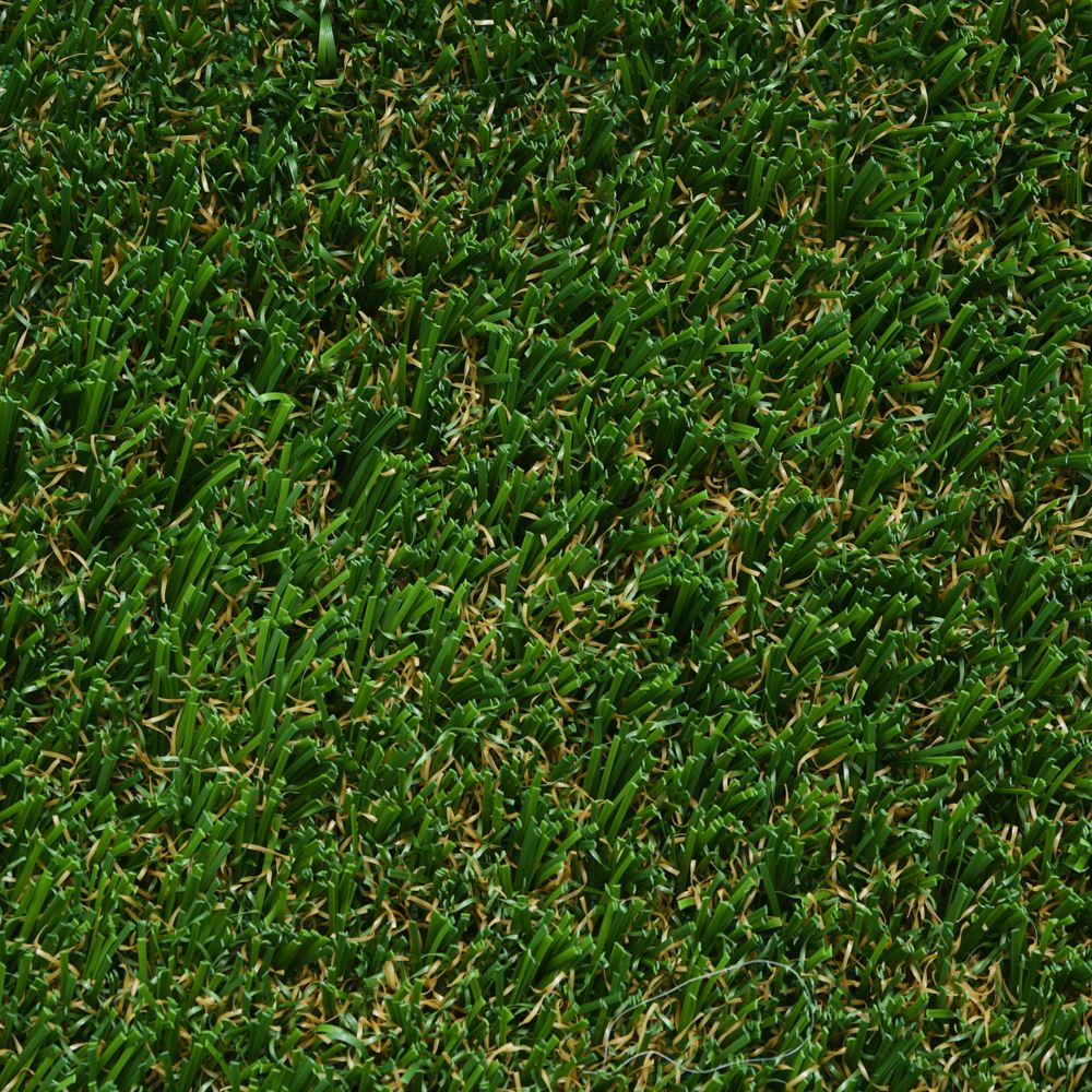 Close up image of green artificial grass with some brown strands.